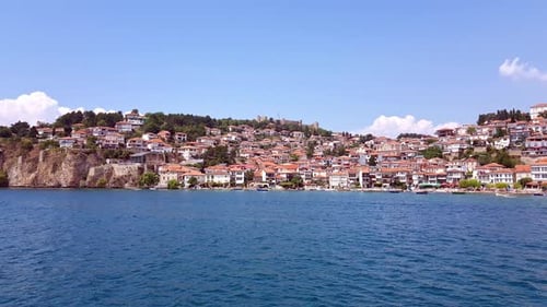 Beautiful view of ancient Ohrid City and buildings on harbor from boat on water perspective.
