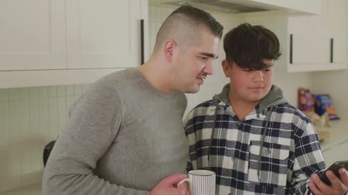 Man and Teen Using a Mobile Phone Indoors