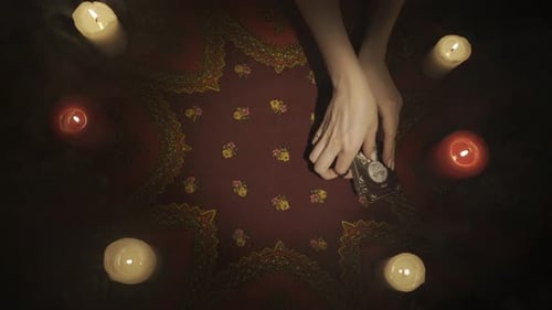 Vue du dessus d'un fan de cartes de tarot posé sur la table avec une carte ouverte, mains féminines enlevant le