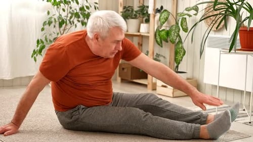 Mature Man Doing Stretches on Carpet at Home