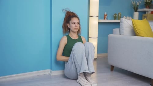 Woman Sitting Curled Up on Floor Indoors