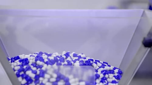 Lab worker scooping capsule pills to cure the coronavirus into a dispenser.