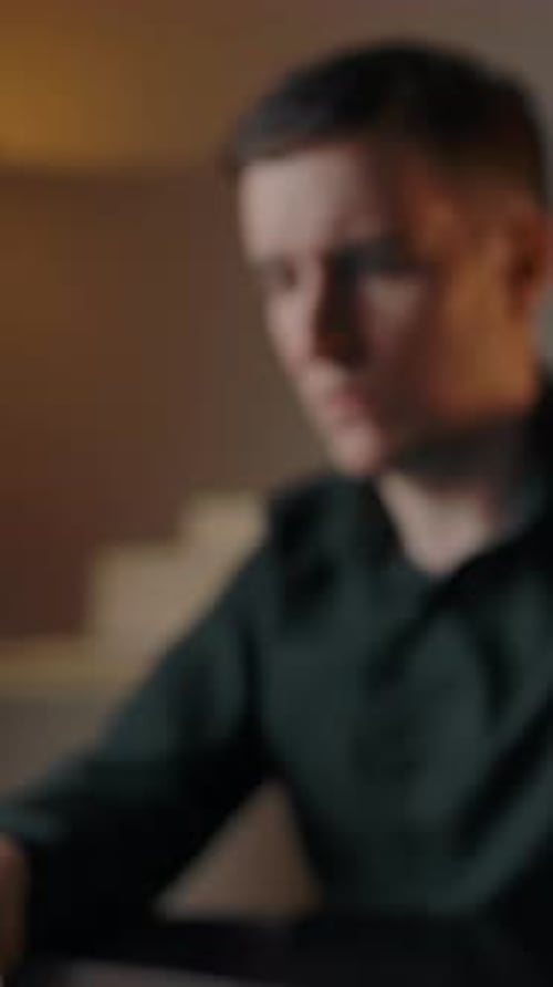 Young Man Working Thoughtfully on Laptop at Night