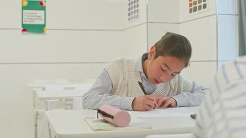Student Writing at Desk in Classroom