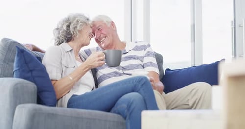 Senior Couple Relaxing Together on Couch Sipping Coffee