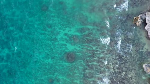 Drone view of beautiful turquiose sea waves breaking on rocky coastline. Aerial shot of golden rocks