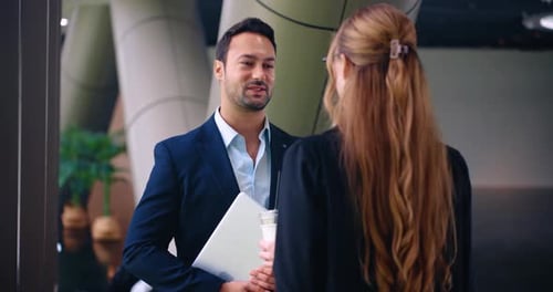 Corporate colleagues having friendly small talk in modern office hallway during business break