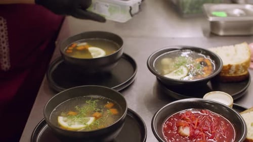 Chef Garnishing Four Bowls of Colorful Soup
