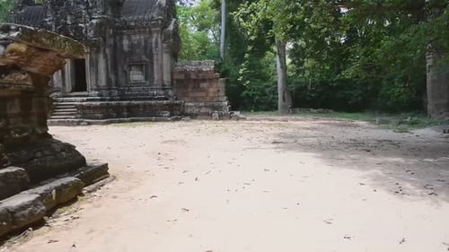 Panning shot of damaged ancient Hindu temple with moss on roof - Siem Reap, Cambodia
