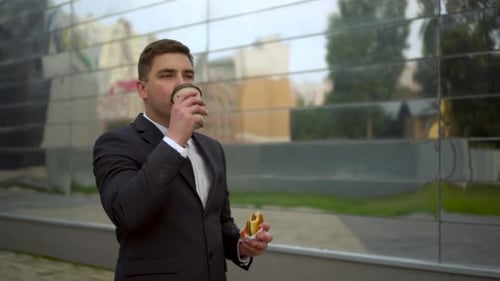 Young Man in Suit Enjoys Coffee and Sandwich