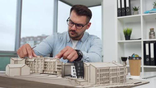 Architect Reviews Building Model in Modern Office