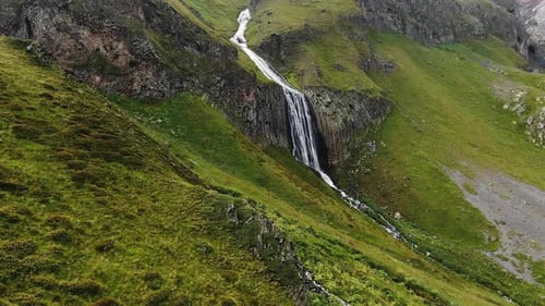Luftaufnahme eines atemberaubenden Bergwasserfalls inmitten grüner Steilhänge
