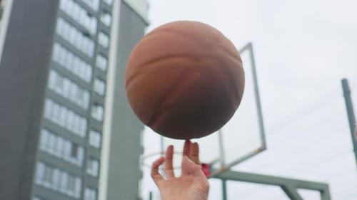 Teenager Spins Basketball on Finger in City Setting