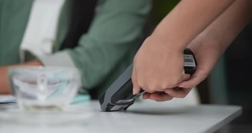Client using credit card machine for non cash payment in cafe.