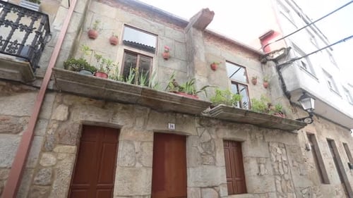 Rustic stone building with wooden doors and balconies decorated with potted plants