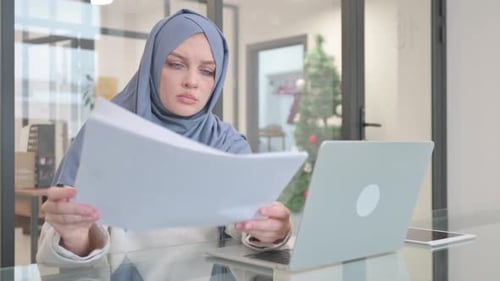 Woman in Hijab Working on Documents and Laptop