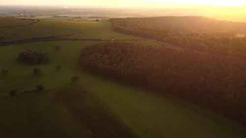 Top down aerial view of a sunset over English countryside. Fields and forest