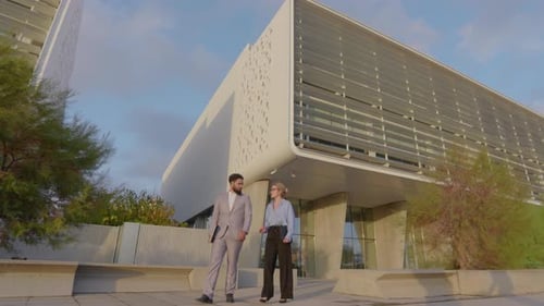 Business Professionals Engaged in Discussion While Walking Near a Modern Office Building