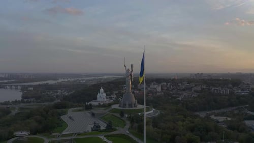 Bandeira ucraniana tremulando ao vento com estátua monumental da pátria e templo da paz no B