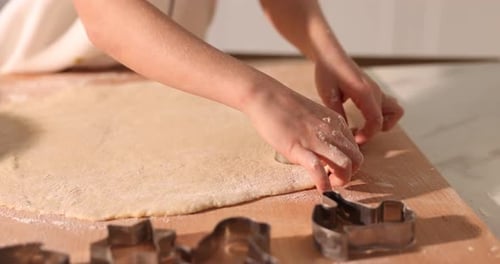 Child Baking Cookies Using Cookie Cutters on Table