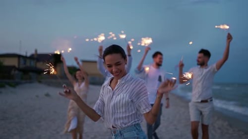 Friends Celebrate on Beach with Sparklers at Twilight
