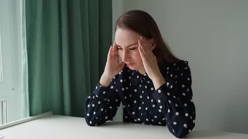 A Young Woman Has a Headache in the Office Attractive Young Beautiful Employee is Sitting at the