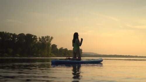 Enjoying a Serene Evening of Paddleboarding at Sunset on a Picturesque Lake Its Truly Captivating