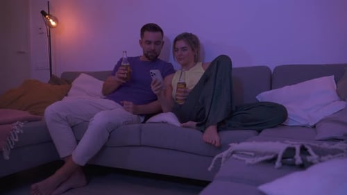 Couple Relaxing with Beer on Sofa at Night