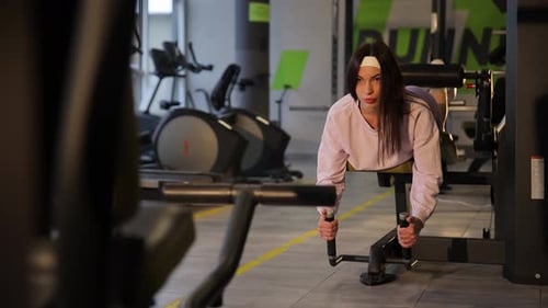 Uma mulher focada que se envolve de todo o coração no treinamento de força na academia com dedicação