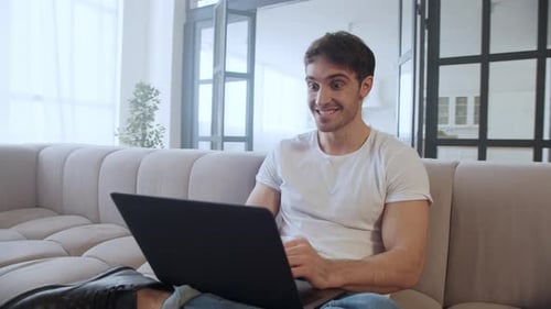 Excited man celebrates success while using laptop