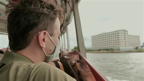 Man Wearing Face Mask Contemplating City View From Boat