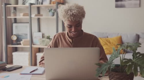 Jeune femme afro-américaine travaillant à la maison dans un espace de travail confortable