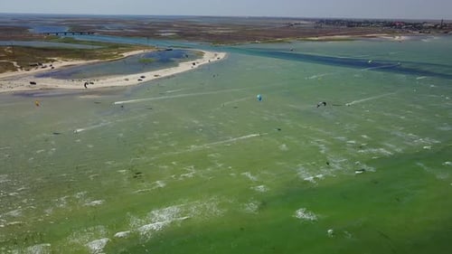 Aerial of Many Kiteboarders with Colorful Kites Flying Over the Blue Sea Lagoon Ride on Kiteboards