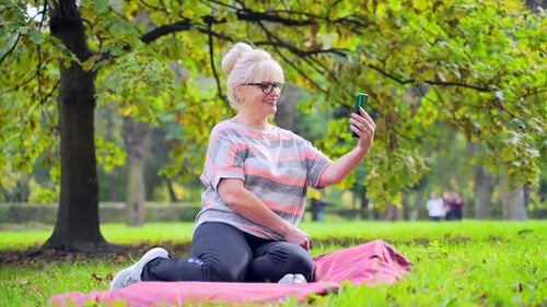 Smiling Woman Taking Selfie with Smartphone in Park