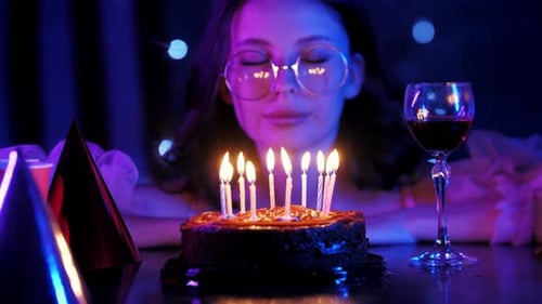 Young Woman Blowing Out Birthday Cake Candles