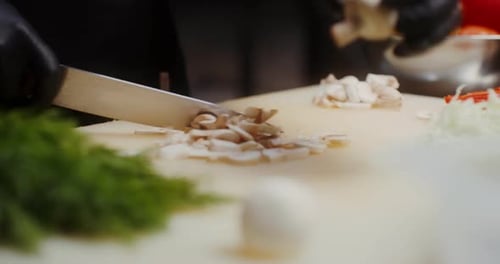 Le chef passe les mains à hacher rapidement des champignons frais sur une planche à découper