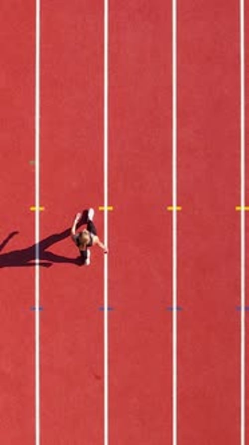 Top Down Aerial Of Young Woman Running On Red Stadium Track