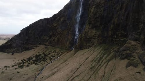 drone flying down from waterfall in the mountains in Iceland