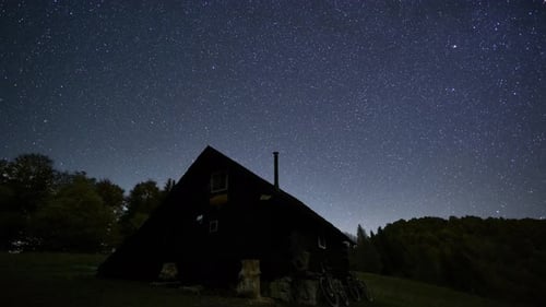 Peaceful Starry Night Sky with Countless Stars Above a Wooden Mountain Hut in Spring Nature