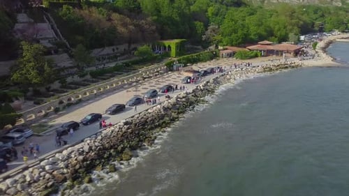 Drone shot of people walking near coastline of Black Sea and Balchik Palace
