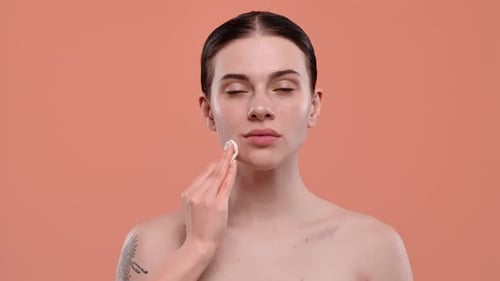 Woman Cleans Face with Cotton Pad