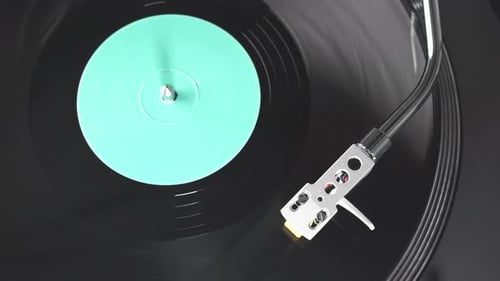 Vinyl record on DJ turntable record player close up. Black vinyl background with a green screen