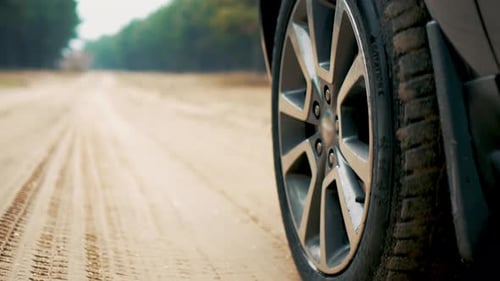 Car Wheel in Sand Close Up Spinning SUV Tire Vehicle Driving By Forest During Family Adventure
