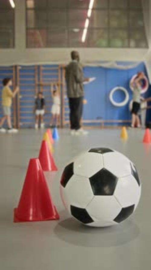 Soccer Ball and Cone at Gym with Children Doing Exercises