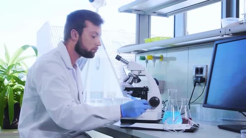 Man Using Microscope in a Bright Laboratory