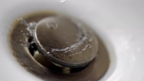 Water Dripping into Bathroom Sink Drain Close Up