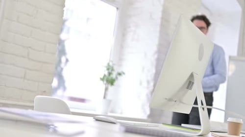 Attractive Working Young Man Coming and Sitting on Office Desk