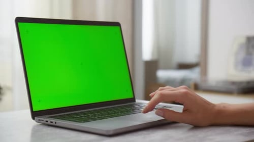Hand Operating Laptop with Green Screen in a Home Environment