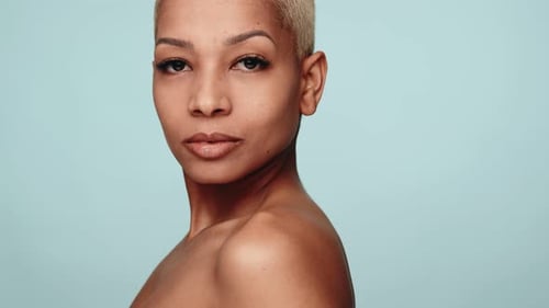 Woman Smiling Softly On Light Blue Background