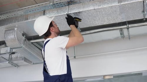 Man Working on Ceiling Ductwork and Metal Bars